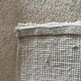 Close-up van de onderzijde van een handgeknoopt Berber tapijt in naturel crèmekleur, met zicht op het knoopwerk en de geweven structuur van 100% zuivere scheerwol. Ambachtelijk vakmanschap en hoogwaardige afwerking – luxe wollen vloerkleed van TTM Wonen voor een stijlvol interieur