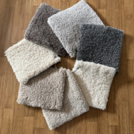 Kleurenwaaier van handgeknoopte Berber tapijten op houten vloer, met stalen in naturel tinten zoals crème, lichtgrijs, antraciet, lichtbruin en donkerbruin. Hoogpolige wollen tapijten van TTM Wonen – perfect voor een warm en stijlvol interieur in natuurlijke kleuren
