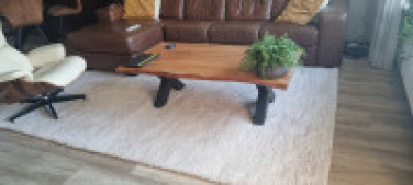 Handgeknoopt naturel Berber tapijt in crèmekleur – sfeervolle woonkamerinrichting met houten salontafel, leren bank en design loungestoel. Luxe wollen vloerkleed van TTM Wonen – ideaal voor een warm en stijlvol interieur.